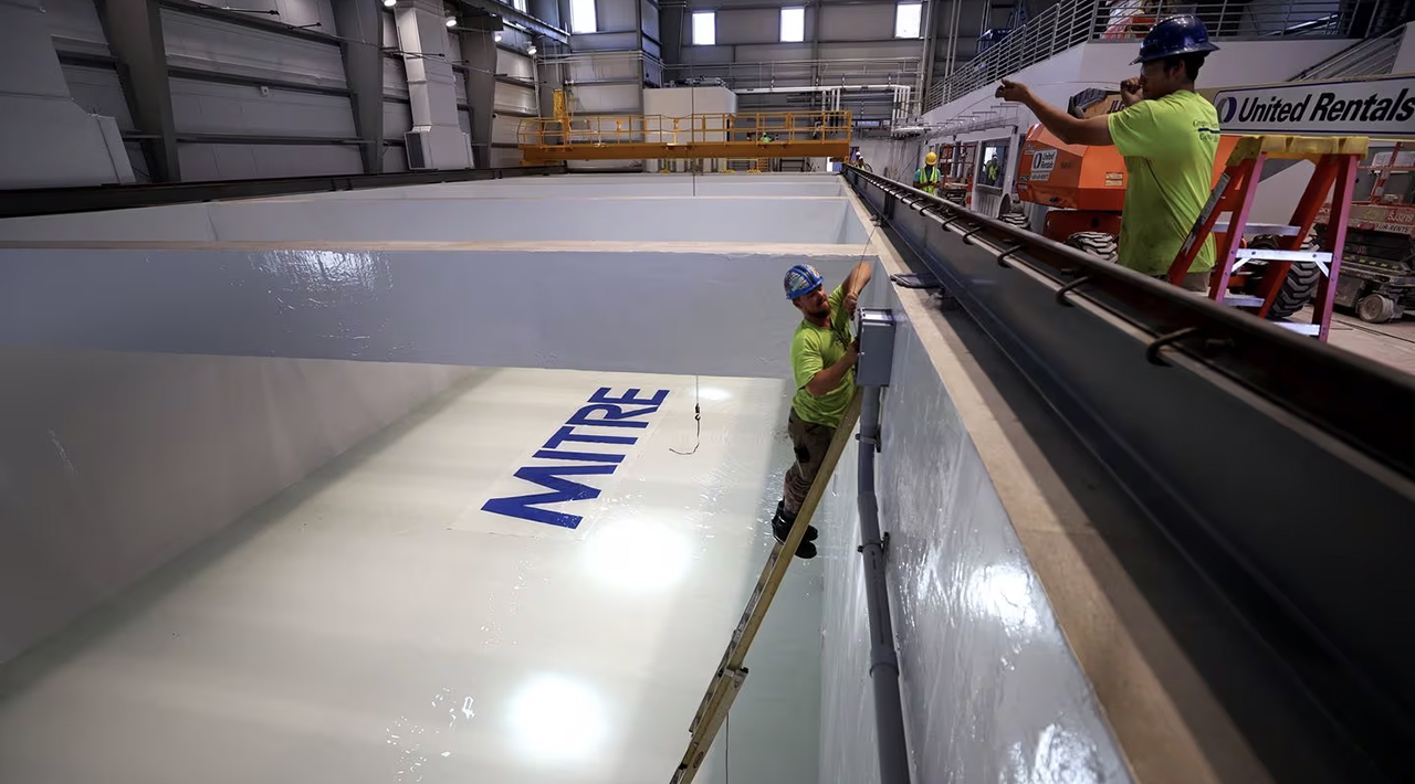 Photo of the MITRE BlueTech pool without water in it. The MITRE logo appears on the bottom of the pool.